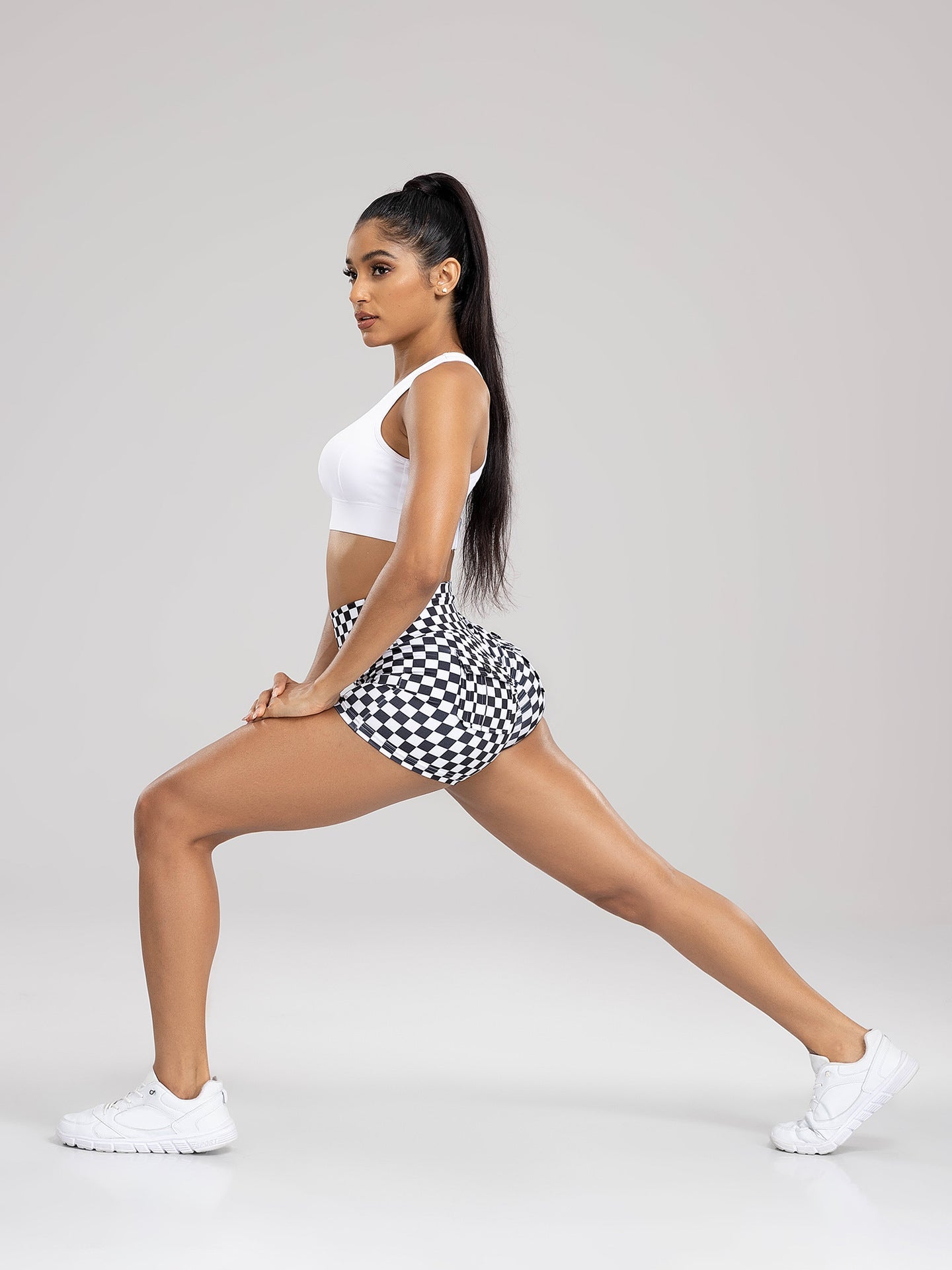 Woman in a checkered sports outfit posing against a plain background